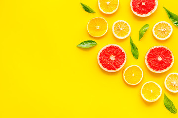 Citrus slices frame - lemons, grapefruits, leaves - on yellow background top-down copy space