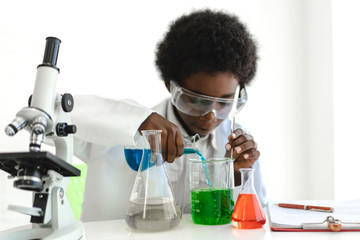 African american boy students learning and doing a chemical experiment and holding test tube in hands in science class on the table.Education concept