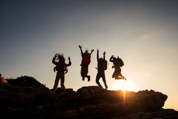 Climbing group friends jumping on top mountain and amazing sunset sky .