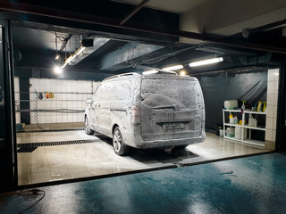 Big minivan car being washed with soap and foam on the carwash at garage