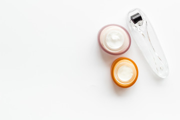 Dermaroller for mesotherapy near creams on white background top-down copy space
