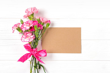 colorful bouquet of different pink carnation flowers, white notebook on white wooden background Top view Flat lay Holiday card 8 March, Happy Valentine's day, Mother's day concept Mock up