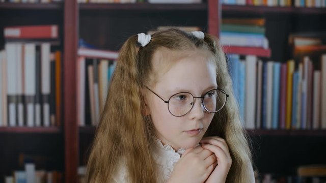 Worried small girl cribbing from paper during exam. Little schoolgirl taking crib sheets from collar. Cheating on exam concept