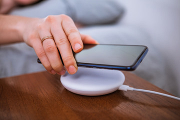 woman hand close up putting phone on wireless charger