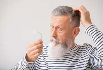 Senior man with hair loss problem at home