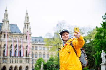 Obraz premium turysta turysta mężczyzna biorąc selfie na telefon wiedeński ratusz na tle
