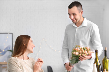 Beautiful young woman receiving flowers from her boyfriend on romantic date in cafe