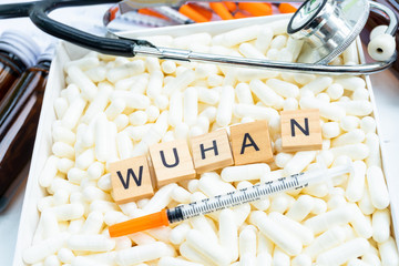 Wuhan virus keyword on wood block on the top of medical pill