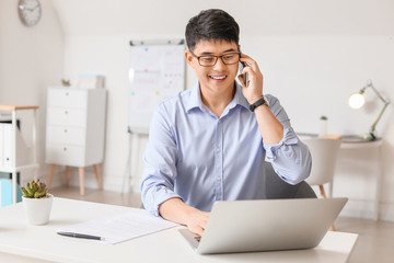 Young Asian businessman talking by phone in office