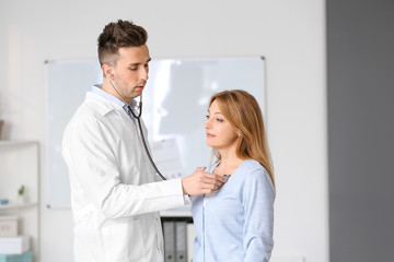 Male cardiologist examining female patient in clinic