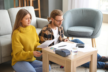 Worried young couple in debt at home