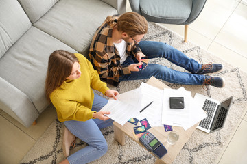 Worried young couple in debt at home, top view