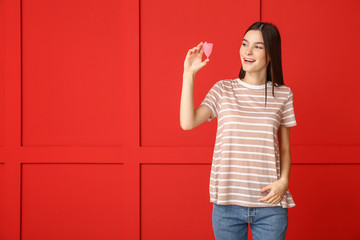 Young woman with menstrual cup on color background