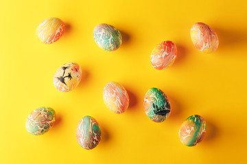 Easter eggs painted in orange and green colors on yellow background, flat lay, space for text