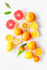 Fresh citrus background. Oranges, grapefruits, leaves - whole fruits and halfs - on white background top-down