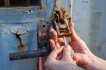 Close up hands trying to unlock an old and rusty padlock 