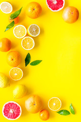 Fresh citrus frame. Oranges, tangerines, grapefruits, leaves on yellow background top-down copy space