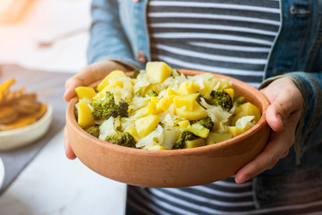 Potato, cabbage vegetables stew Woman hands holds ragout. Vegan healthy diet food.