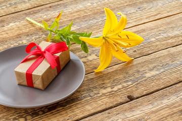 Top view of gift box with lily flower on the wooden background.