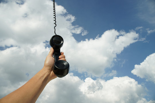 vintage black phone with line hanging from the sky. Conceptual photography talking to someone from above