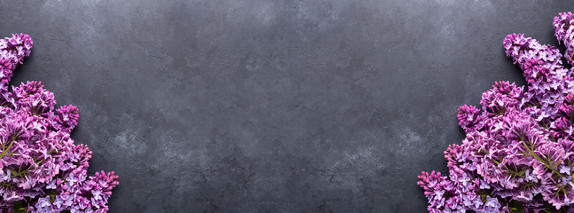 Beautiful purple lilac on dark stone background. Top view. Copy for your text. Long horizontal banner