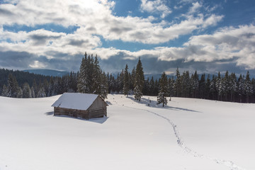 Charming snow-capped houses on a mountain Carpathian mountain valley, with magnificent views of peaks in winter.