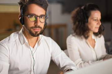 Handsome call center operator in eyeglasses looking at camera. Confident young man looking at camera. Call center concept