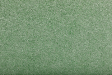 simple surface of sheet of cardboard is green. Rough background paper texture with cellulose fibers. Macro