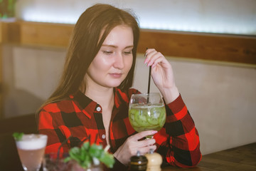 Young woman drinks a cocktail from a glass.