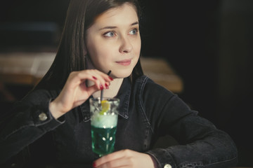 Young woman drinks a cocktail from a glass.
