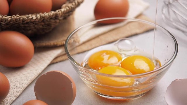 ME CU LD Slow motion of falling egg into a transparent bowl in kitchen to prepare food, desserts, bakery items, etc.