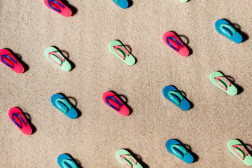 Pattern of beach colorful sandals or thongs on a sandy beach.