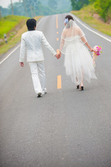 Fototapeta na wymiar Wedding couple in wedding cloths walking along the road
