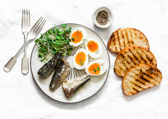 Grilled bread, sardines, boiled eggs, micro greens on a light background, top view. Delicious breakfast, tapas, appetizers
