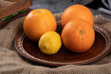 Orange and lemon in a brown decorative platter.