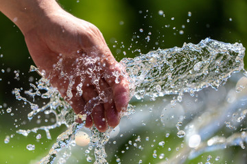 Fototapeta premium Hand of a man in the spray of water of the fountain