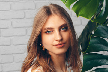 Fototapeta premium Portrait of a beautiful woman with monstera leaves. Creative photo