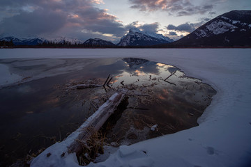 Reflection in frozen lake in the mountains - Banff National Park, Alberta,  Canada.