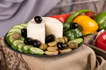 White cheese platter with cucumber and olives