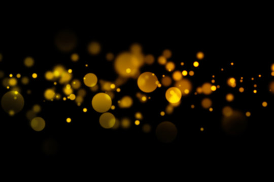 Golden light bokeh and abstract glittering on dark background. Sparkling dust particles.