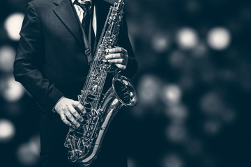 Saxophone player isolated at the left border of a black background