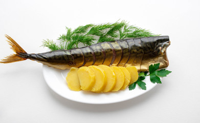 Plate with baked mackerel stuffed with herbs, onions and boiled potatoes with spices and butter on a textured white background, selective focus.