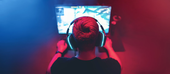 Blurred background professional gamer playing tournaments online games computer with headphones, red and blue - obrazy, fototapety, plakaty