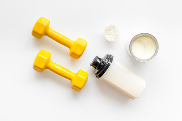 Sport nutrition. Whey protein, shaker, dumbbells on white background top-down flay lay