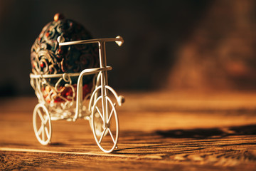 Vintage Easter egg on bike. Bicycle retro photo on wooden background.