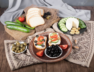 Tomato cucumber sandwiches with olives in a brown platter.