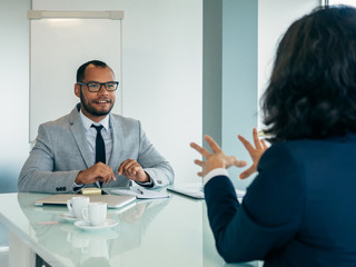 Excited male employer interviewing female applicant. Business man and woman sitting at conference...