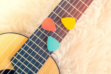 colorful pick on small acoustic guitar fretboard. music background