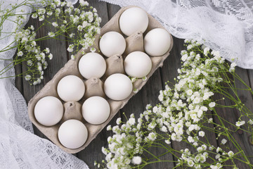 Happy Easter. White eggs in a stand on a wooden background with white gypsophila flowers. Holidays concept. Trend.