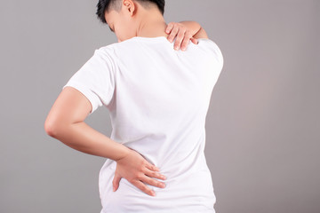 Asian people suffering from back pain on a gray background. Health concept.